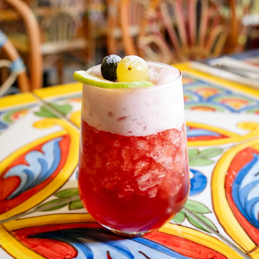 Cocktail glacé aux fruits rouges, servi sur une table en faïence peinte.