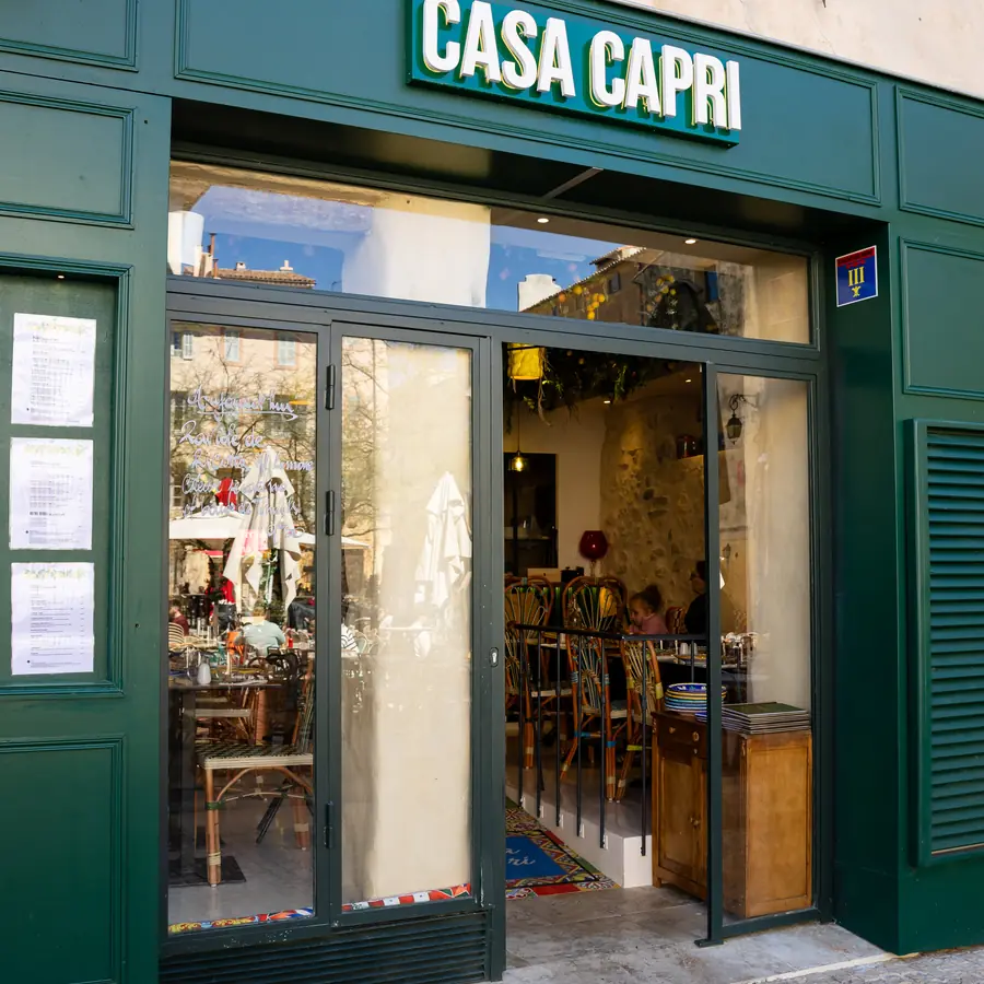 La devanture verte de Casa Capri sur la Place des Cardeurs, portes ouvertes sur la salle.